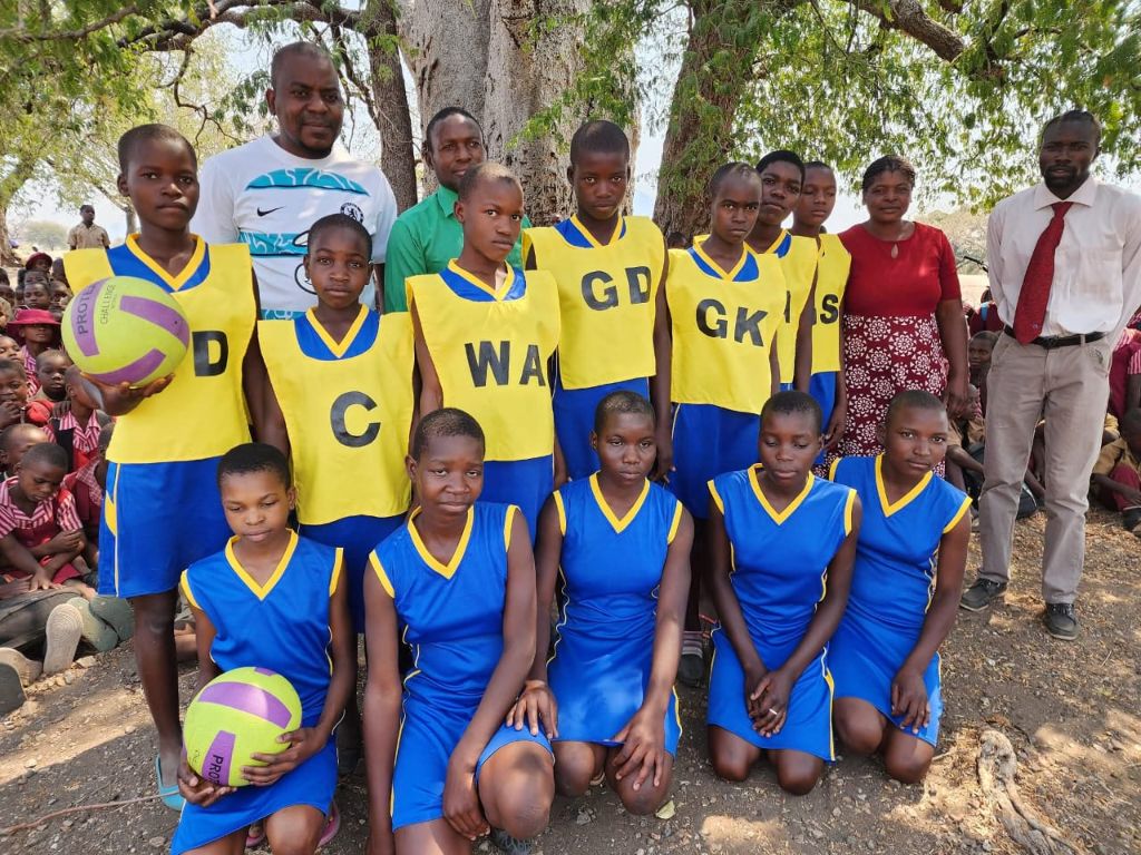 Girls netball team in full kit with teachers at the handover ceremony